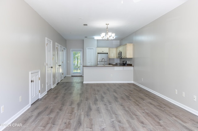 kitchen with kitchen peninsula, hanging light fixtures, a chandelier, light wood-type flooring, and cream cabinetry