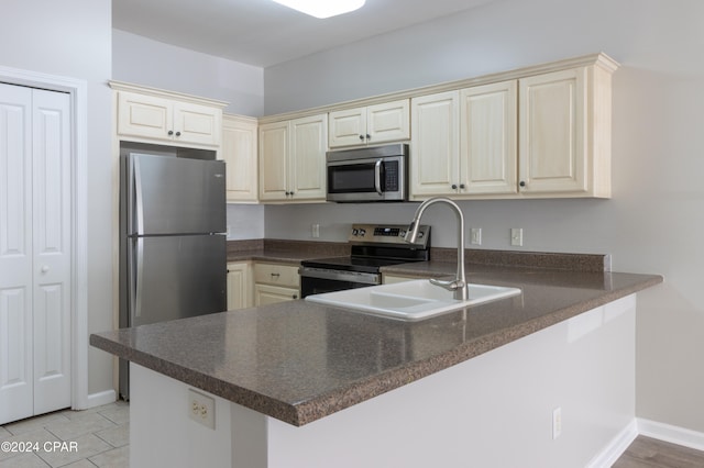 kitchen featuring sink, cream cabinetry, light tile patterned flooring, kitchen peninsula, and stainless steel appliances