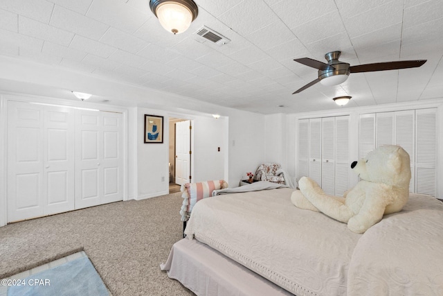 carpeted bedroom with two closets and ceiling fan