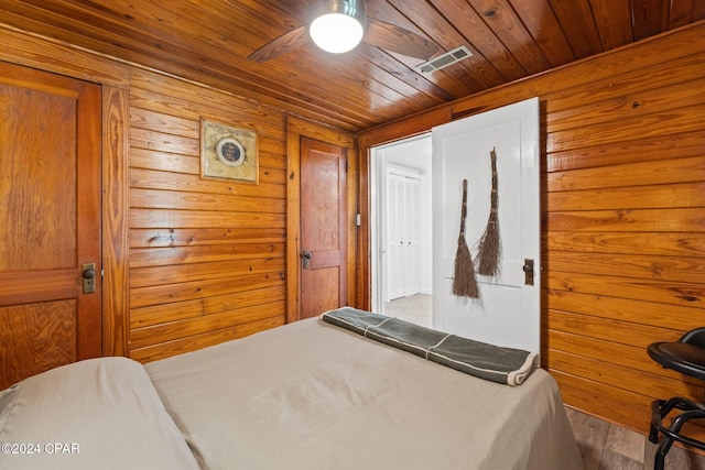 bedroom featuring hardwood / wood-style flooring, wood walls, ceiling fan, and wood ceiling