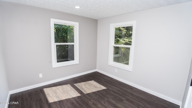 spare room with a textured ceiling and dark hardwood / wood-style flooring