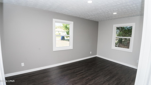 spare room featuring dark hardwood / wood-style floors and a textured ceiling