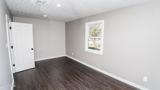 empty room with a textured ceiling and dark hardwood / wood-style flooring