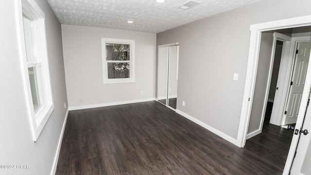 unfurnished bedroom with baseboards, dark wood finished floors, and visible vents