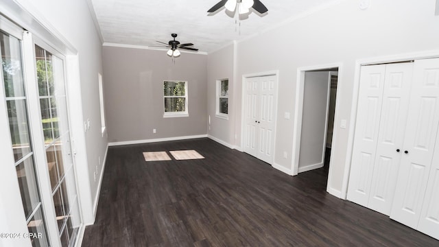 unfurnished bedroom featuring multiple closets, ornamental molding, and dark wood-style flooring