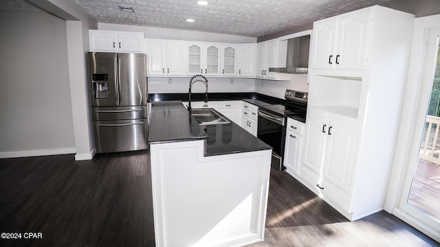 kitchen with wall chimney range hood, dark countertops, appliances with stainless steel finishes, a sink, and dark wood-style floors