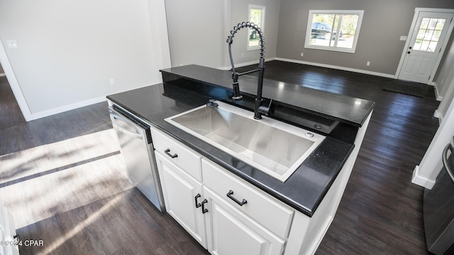 kitchen featuring a sink, dark countertops, stainless steel dishwasher, and dark wood-style floors