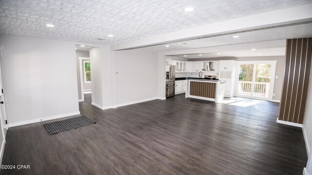 unfurnished living room with a textured ceiling, sink, and dark hardwood / wood-style floors