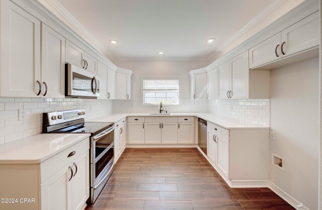 kitchen featuring white cabinetry, crown molding, stainless steel appliances, and hardwood / wood-style floors