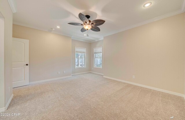 empty room featuring crown molding, light colored carpet, and ceiling fan