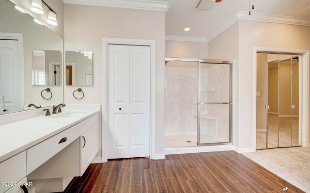 bathroom with vanity, hardwood / wood-style floors, a shower with shower door, and ornamental molding