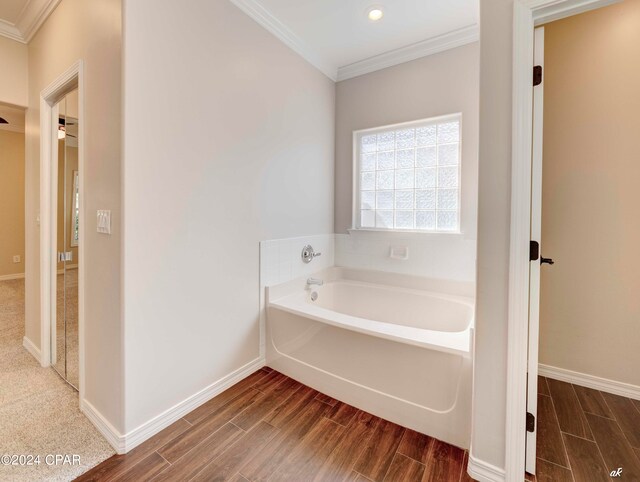 bathroom featuring ornamental molding, hardwood / wood-style flooring, and a bath