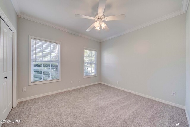 spare room with ornamental molding, light colored carpet, and ceiling fan