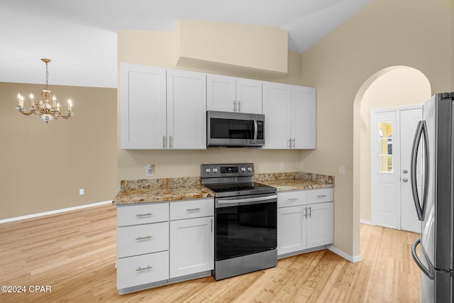 kitchen with light wood-type flooring, white cabinetry, stainless steel appliances, vaulted ceiling, and light stone counters