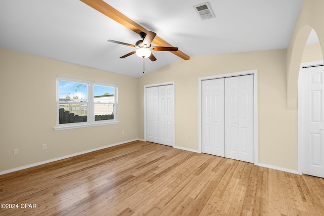 unfurnished bedroom featuring multiple closets, lofted ceiling with beams, light wood-type flooring, and ceiling fan