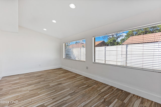 empty room with hardwood / wood-style floors and vaulted ceiling