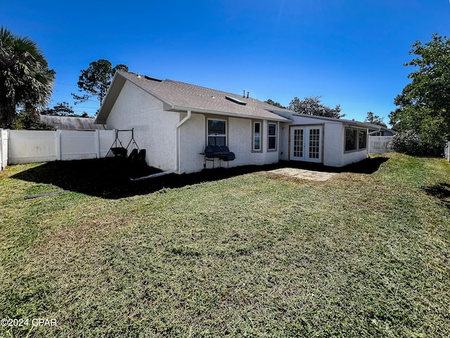 rear view of house featuring french doors and a lawn