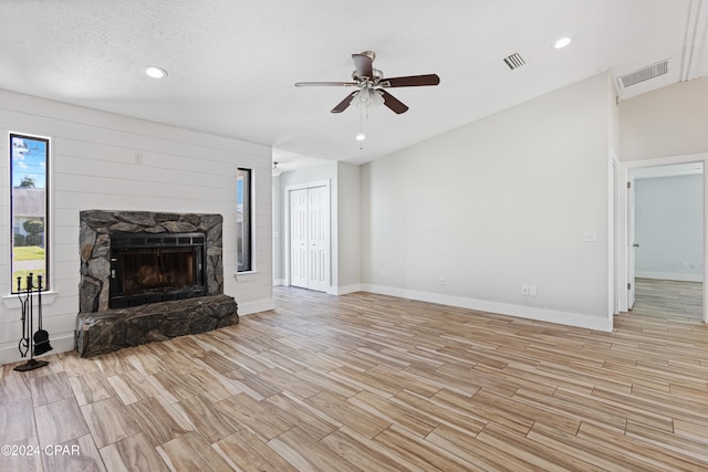 unfurnished living room with a textured ceiling, light wood-type flooring, and ceiling fan