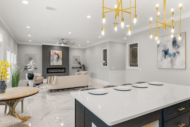 kitchen featuring ornamental molding, a kitchen island, decorative light fixtures, and ceiling fan with notable chandelier