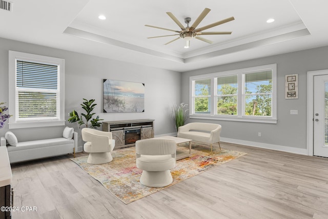 living room with a tray ceiling, plenty of natural light, and light wood-type flooring