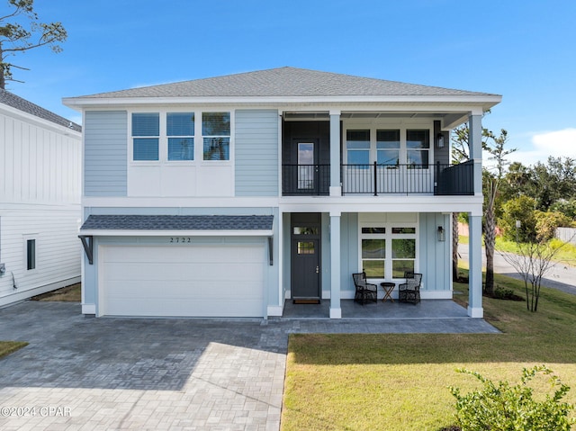 view of front facade featuring a front yard, a balcony, and a garage