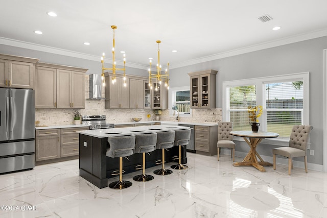 kitchen featuring wall chimney range hood, hanging light fixtures, appliances with stainless steel finishes, a chandelier, and a center island