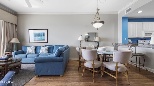 living area featuring baseboards, crown molding, visible vents, and wood finished floors