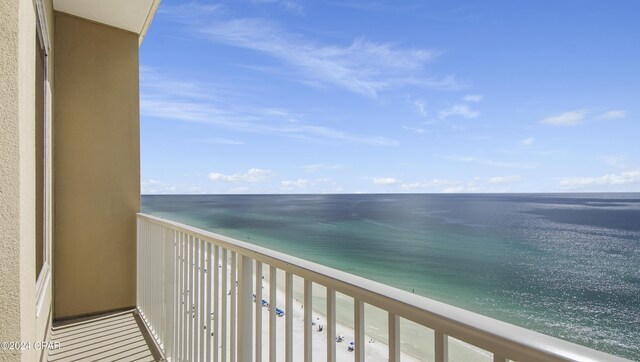 balcony with a water view and a view of the beach