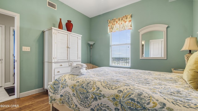 bedroom with baseboards, visible vents, and wood finished floors