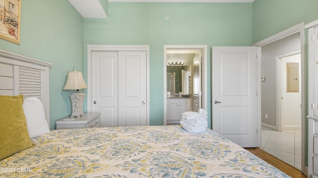 bedroom with a closet, ensuite bath, and wood finished floors