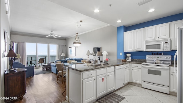 kitchen with white appliances, visible vents, open floor plan, white cabinetry, and a sink