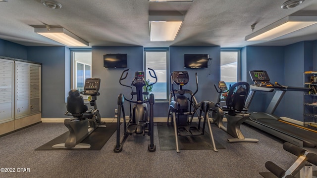 workout area featuring a wealth of natural light, baseboards, a textured ceiling, and mail area