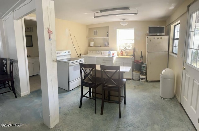 kitchen with white cabinets, washer and clothes dryer, white appliances, and concrete floors