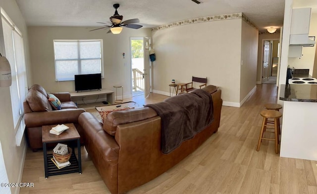 living room featuring light wood-type flooring, a textured ceiling, and ceiling fan