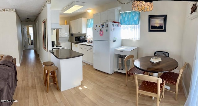 kitchen with white cabinets, white appliances, hanging light fixtures, and light wood-type flooring