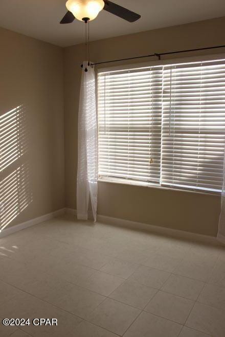 tiled spare room featuring ceiling fan