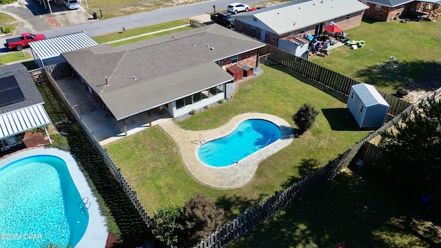 view of swimming pool featuring a yard, a storage shed, and a patio area