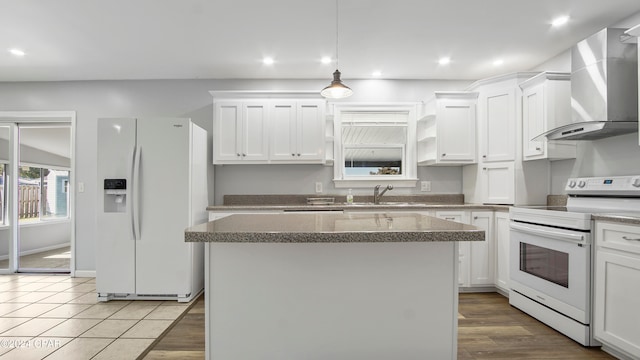 kitchen featuring wall chimney exhaust hood, light hardwood / wood-style flooring, sink, white cabinetry, and white appliances