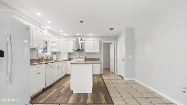 kitchen with white appliances, a kitchen island, hanging light fixtures, white cabinetry, and light hardwood / wood-style floors