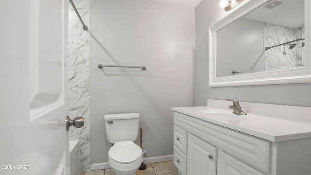 bathroom with vanity, a tile shower, toilet, and tile patterned floors