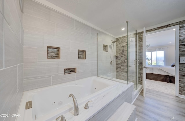 bathroom with hardwood / wood-style flooring, tile walls, and independent shower and bath