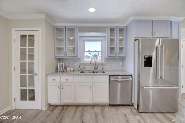 kitchen with sink, a textured ceiling, tasteful backsplash, light hardwood / wood-style floors, and stainless steel appliances