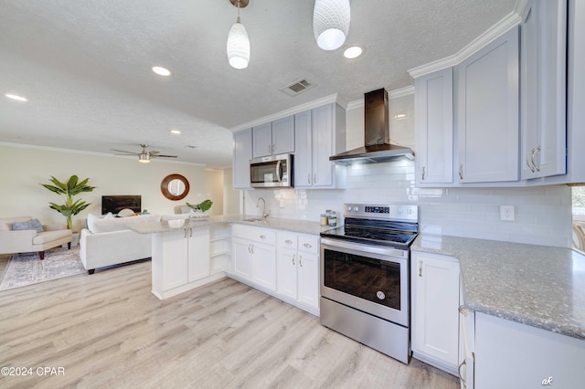 kitchen featuring light hardwood / wood-style flooring, wall chimney exhaust hood, appliances with stainless steel finishes, decorative light fixtures, and kitchen peninsula