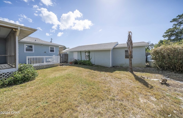 back of property featuring a wooden deck and a lawn