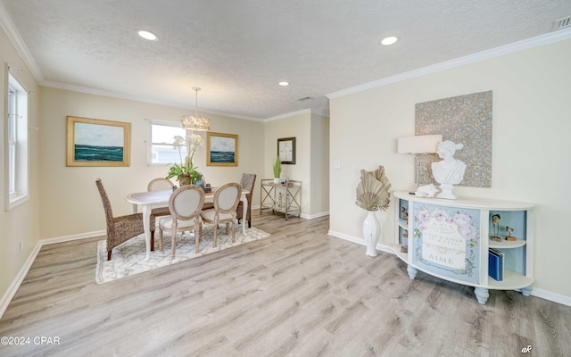 dining room featuring a textured ceiling, light hardwood / wood-style floors, and ornamental molding