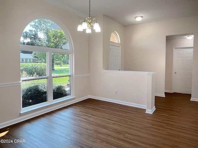 unfurnished dining area with dark wood-type flooring, a notable chandelier, and plenty of natural light