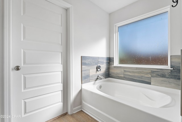 bathroom with a healthy amount of sunlight, wood-type flooring, and a bath