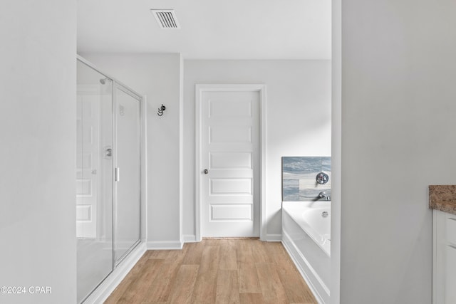 bathroom featuring vanity, hardwood / wood-style floors, and plus walk in shower