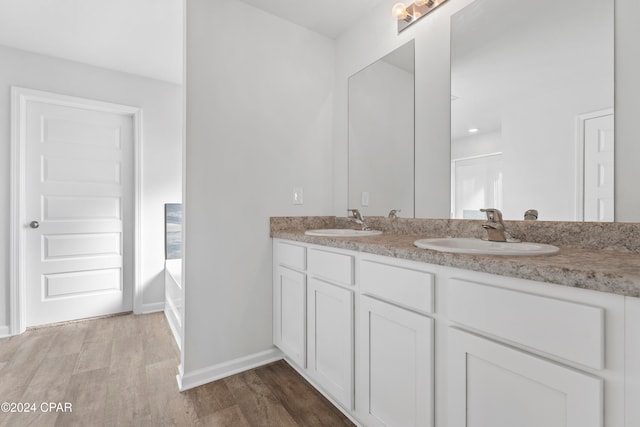 bathroom with vanity, hardwood / wood-style flooring, and a bath