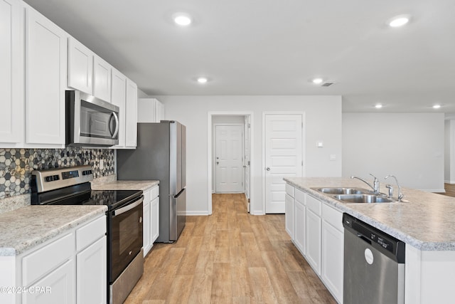 kitchen with light hardwood / wood-style flooring, white cabinets, stainless steel appliances, and an island with sink